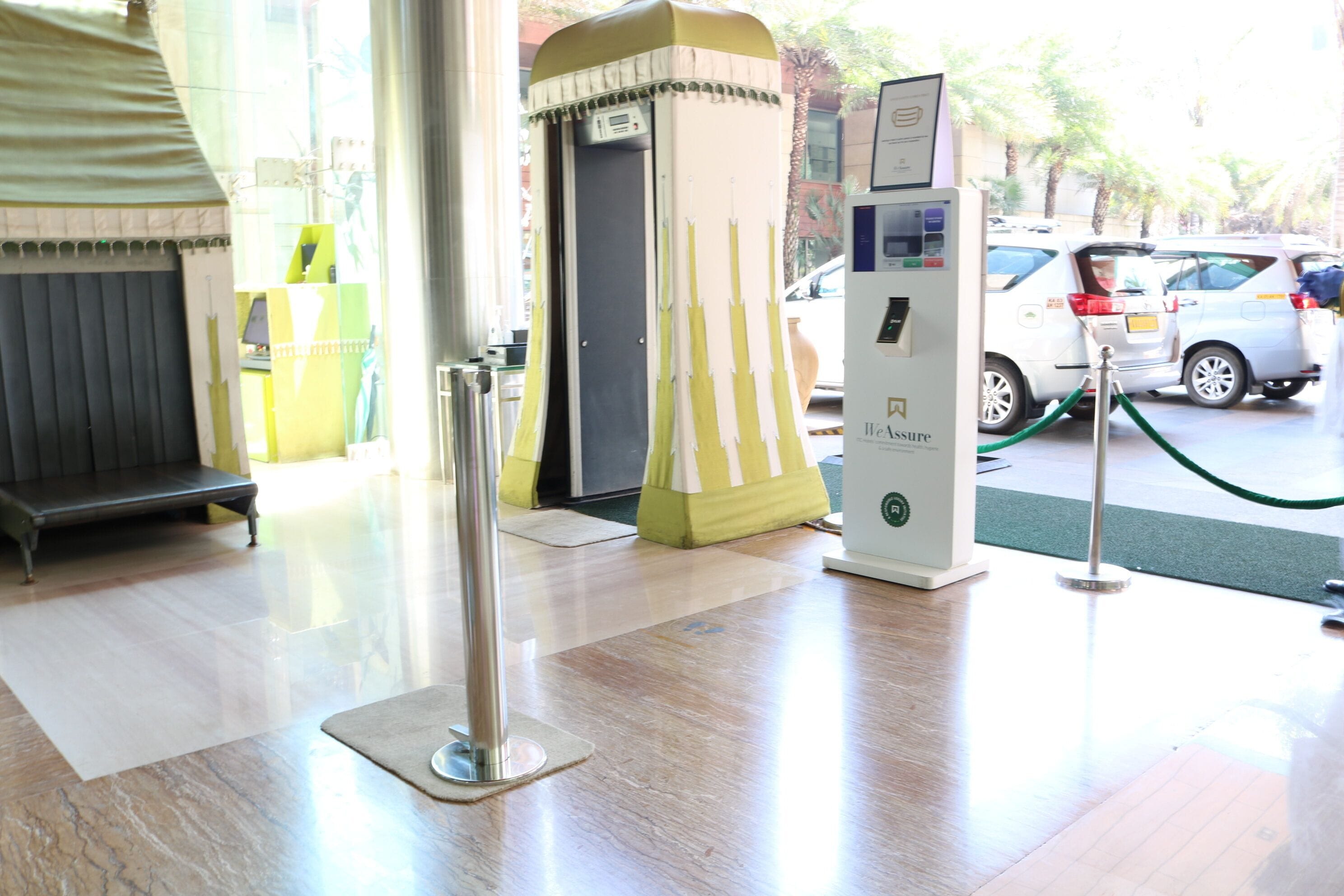 Un vestíbulo de hotel con mostrador de recepción, quiosco de autoservicio y estación de carga para vehículos eléctricos.