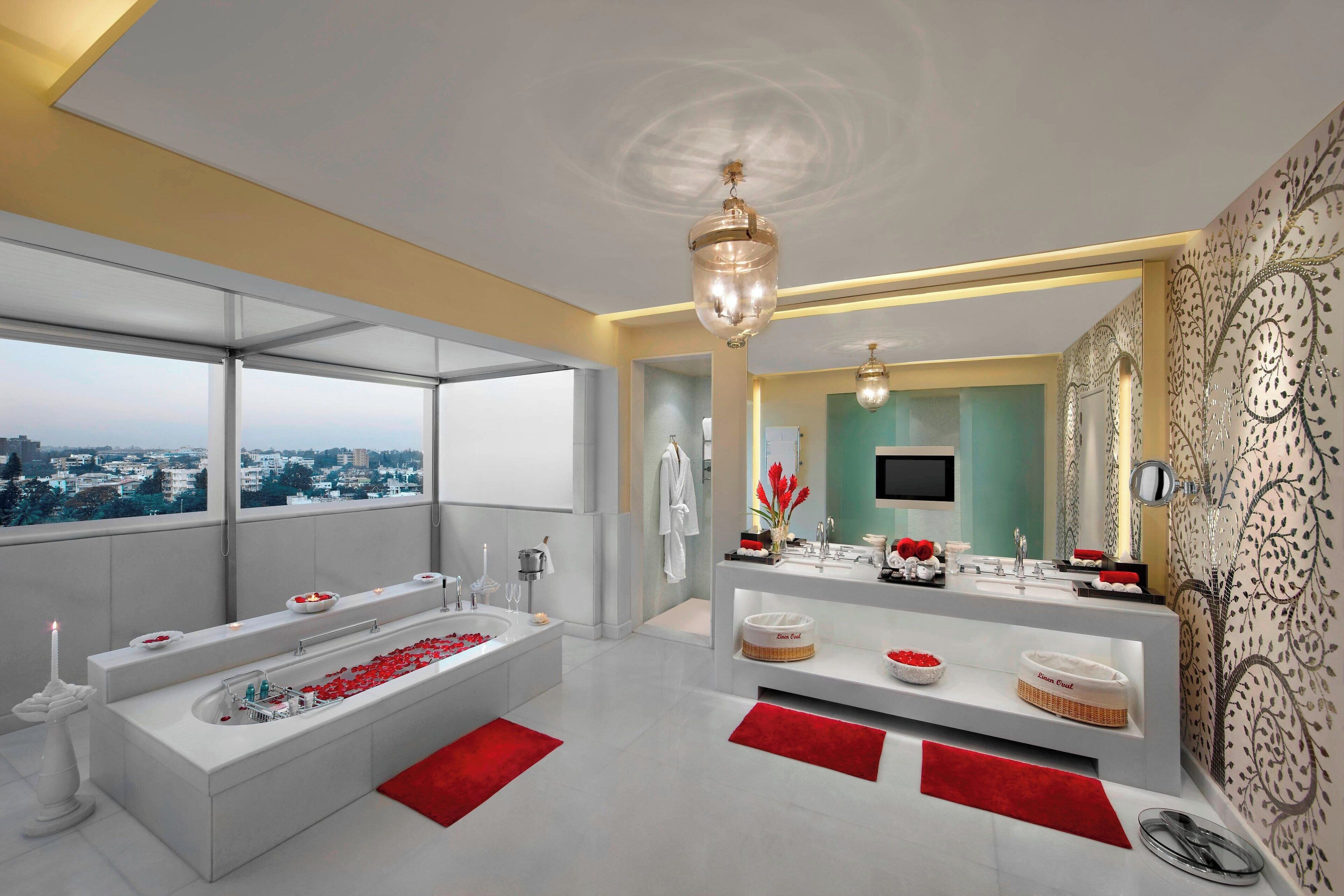 A modern bathroom with a large bathtub, a vanity with a mirror, and a view of the city.