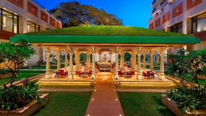 A hotel with a covered outdoor seating area, a central fountain, and a green roof.