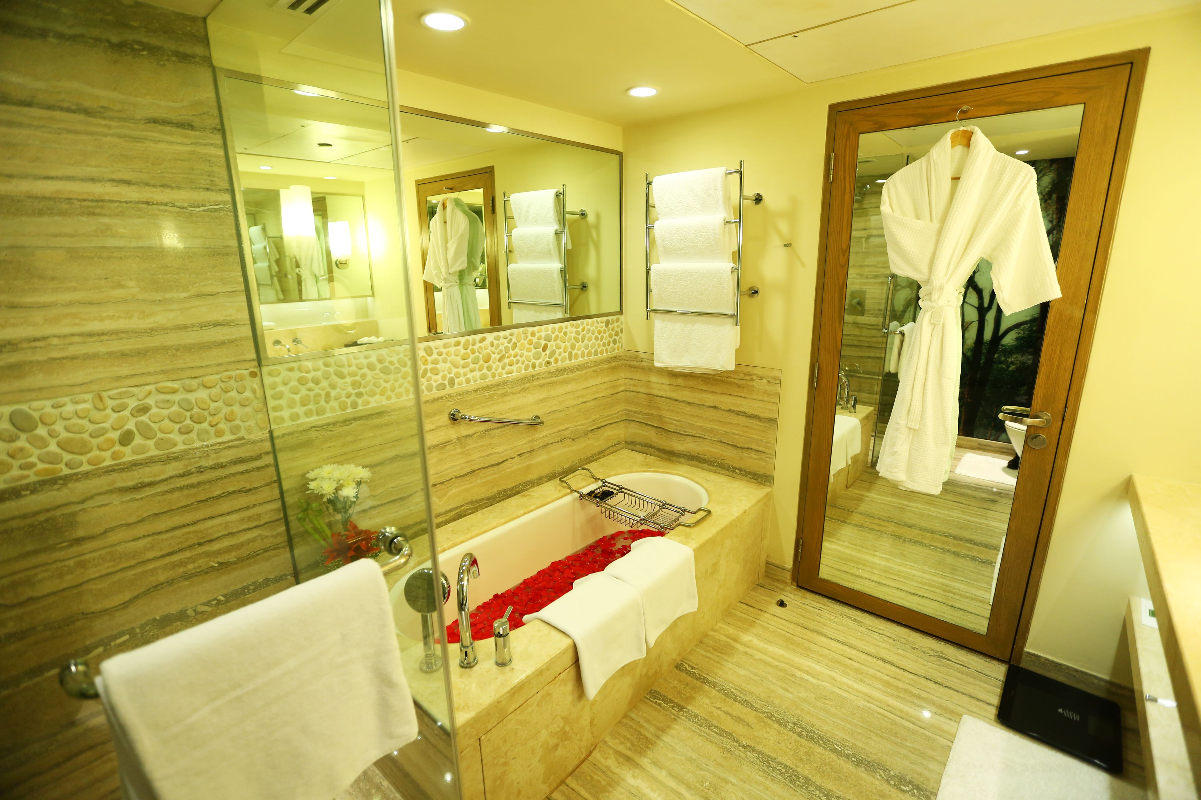 A modern bathroom with a marble sink, a glass-enclosed shower, and a wooden door.