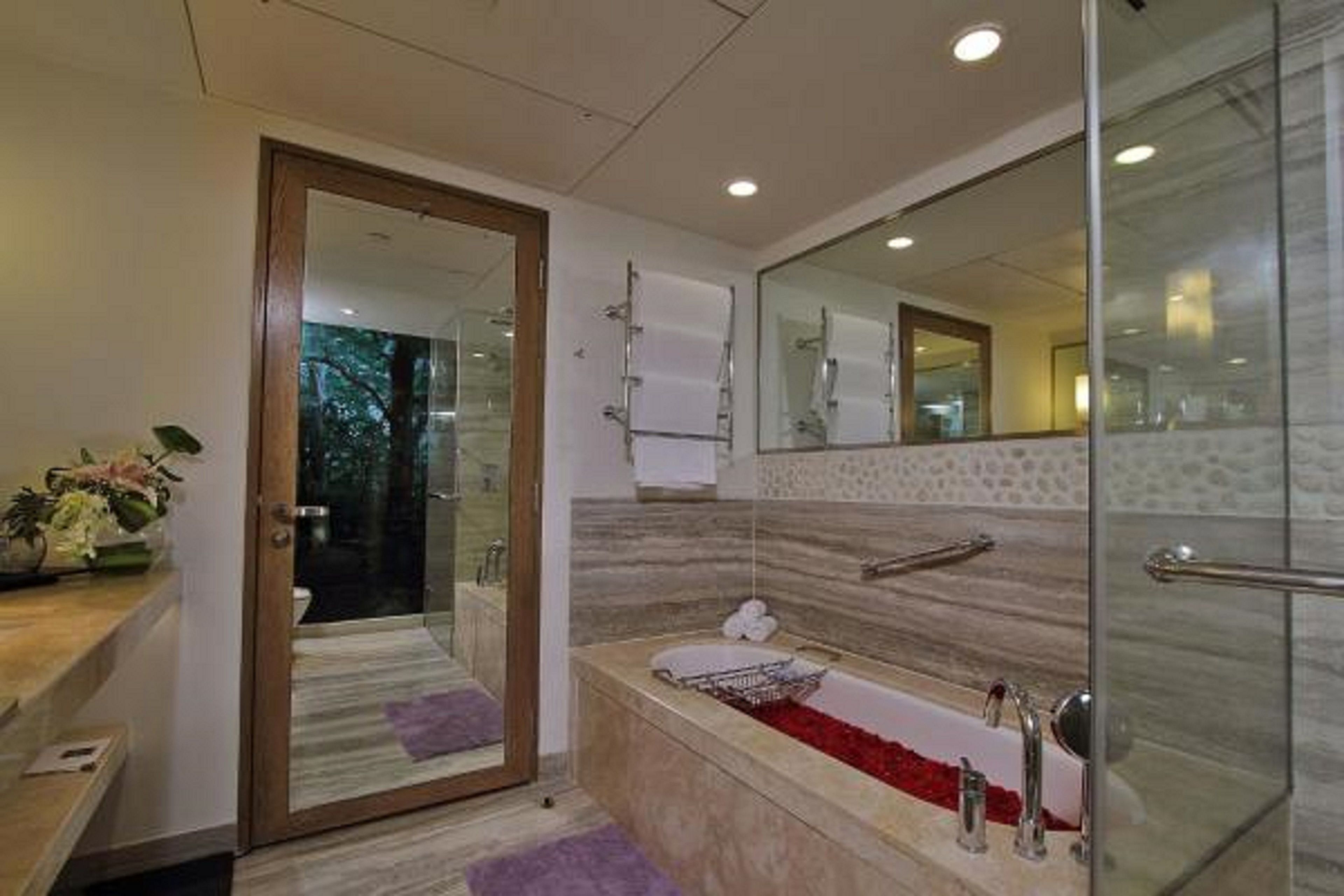 A modern bathroom with a glass shower enclosure, a marble sink, and a large mirror.