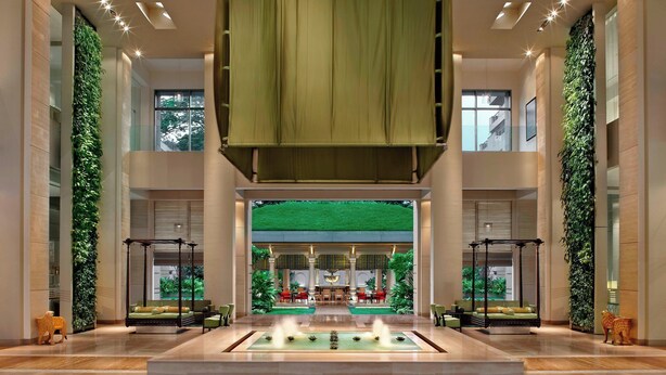 A spacious lobby with a central fountain, seating areas, and vertical gardens.