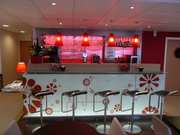 A bar area with a counter, stools, and a red-lit background. - ibis Etampes (Etampes)