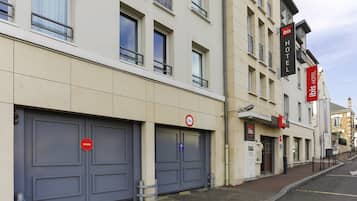 Un hôtel doté d’une façade moderne, de grandes portes doubles grises et d’un panneau indiquant une zone de non-stationnement de 2 mètres.