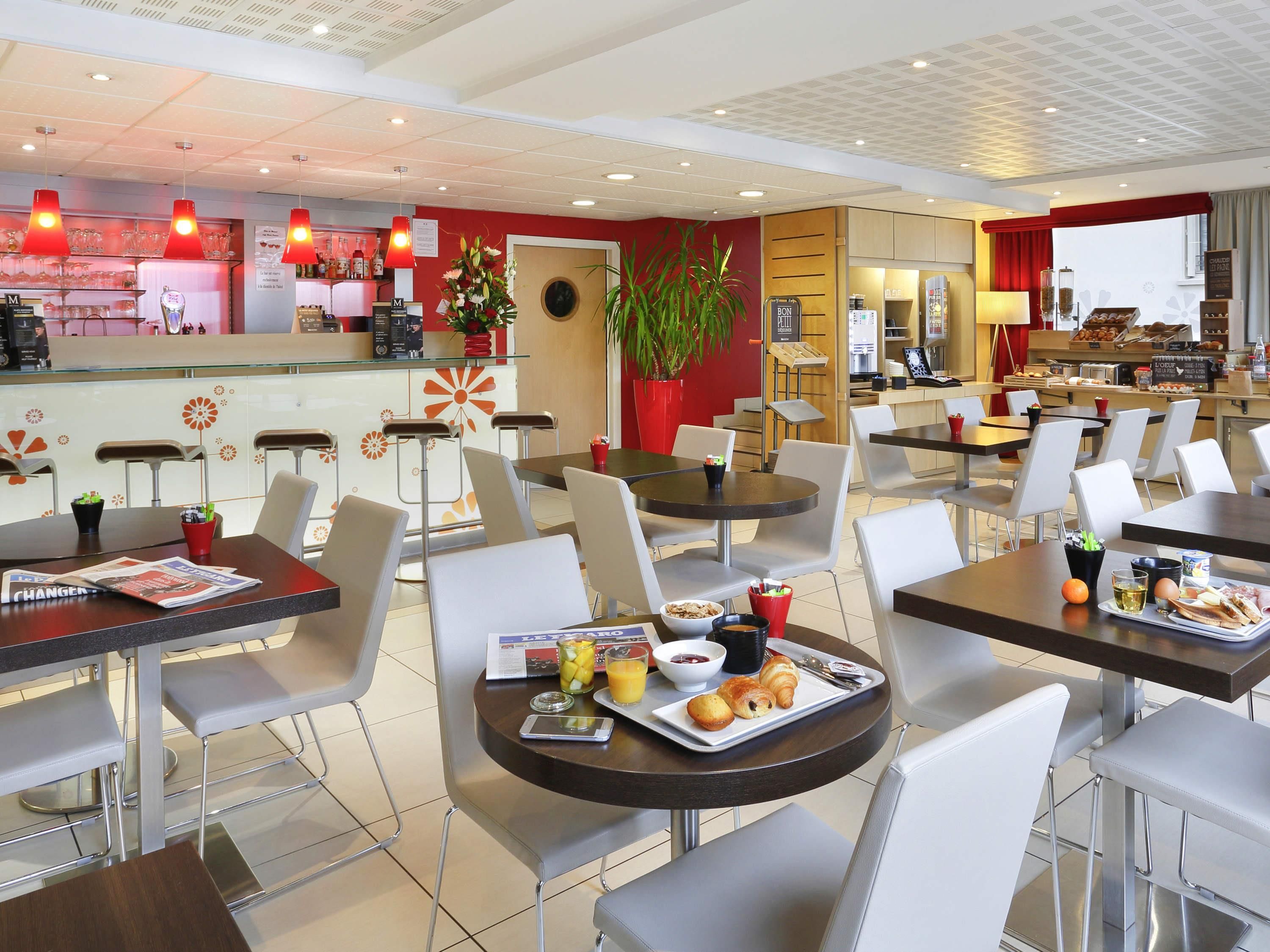 Un café moderno con mesas redondas, sillas blancas y una zona de bar.