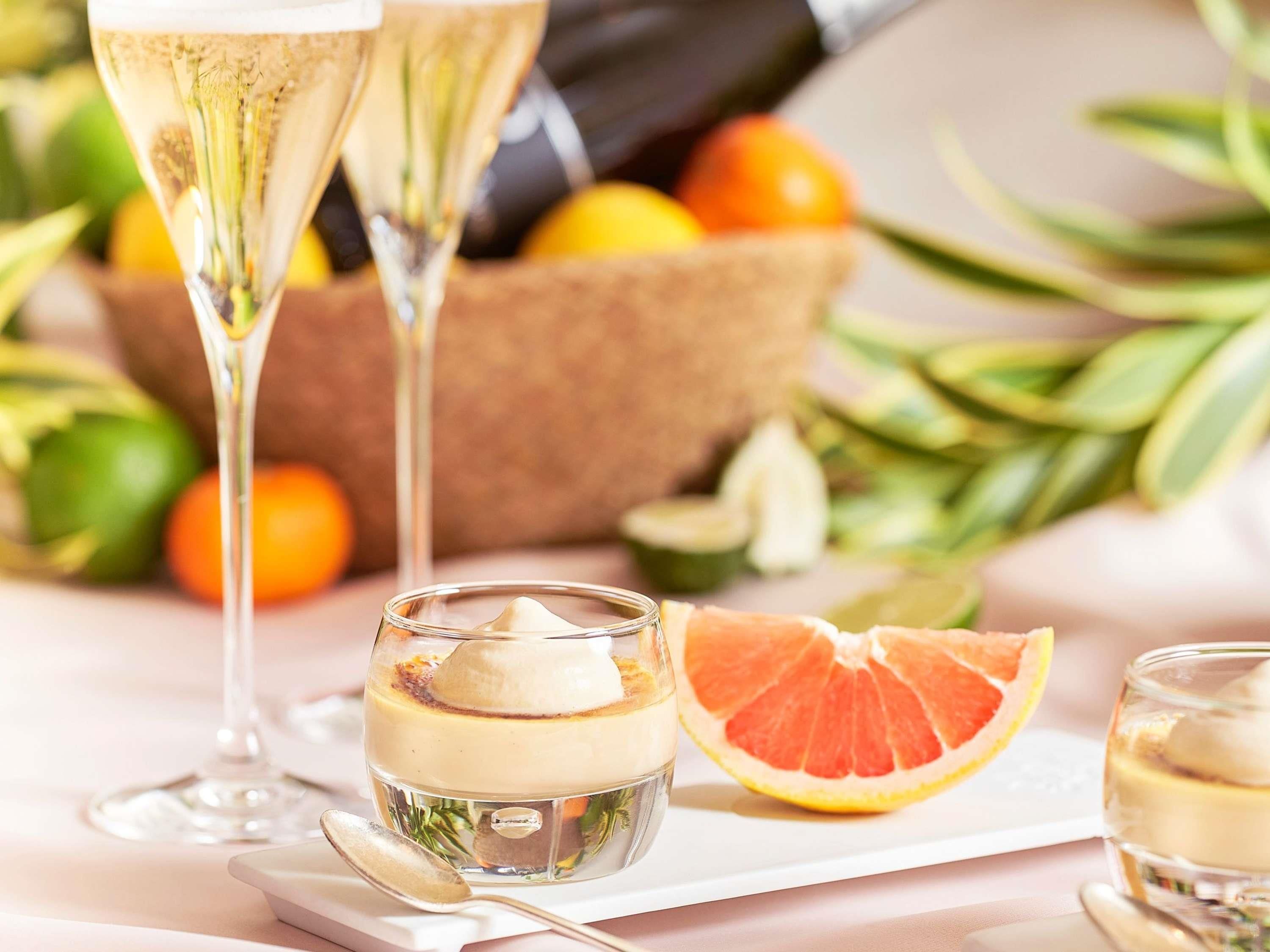 A dessert setting with a glass of champagne, a small glass of dessert, and a halved grapefruit.