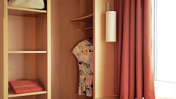 Ein Holzschrank mit Regalen, einem aufgehängten Kleidungsstück und einem Paar Schuhen.