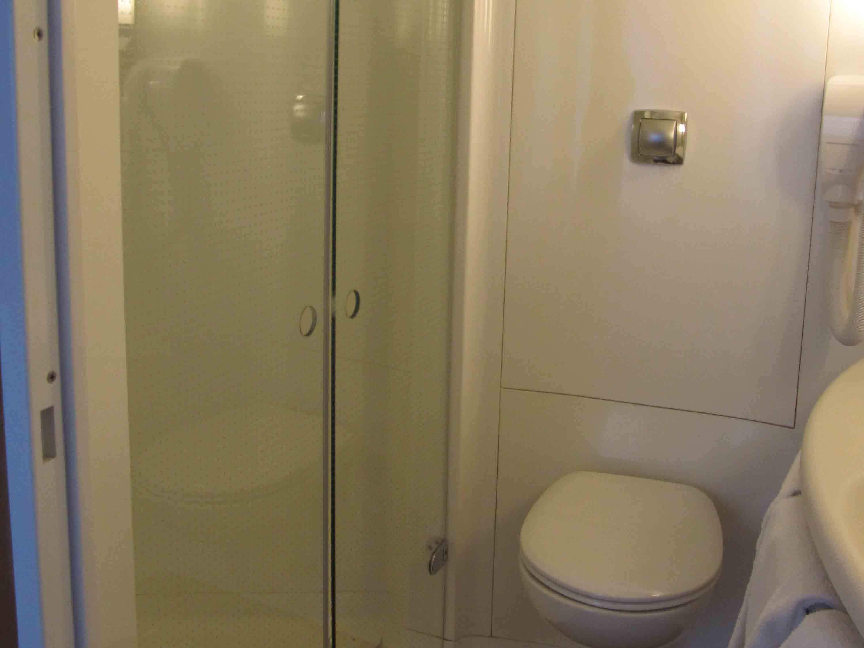 Un baño con cabina de ducha de vidrio, inodoro y lavamanos.