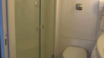 Un baño con cabina de ducha de vidrio, inodoro y lavamanos.