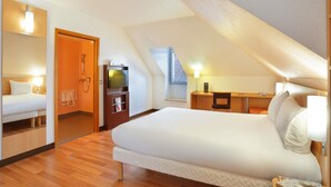 Quarto de hotel moderno com uma cama grande, uma escrivaninha, uma televisão e um chuveiro.