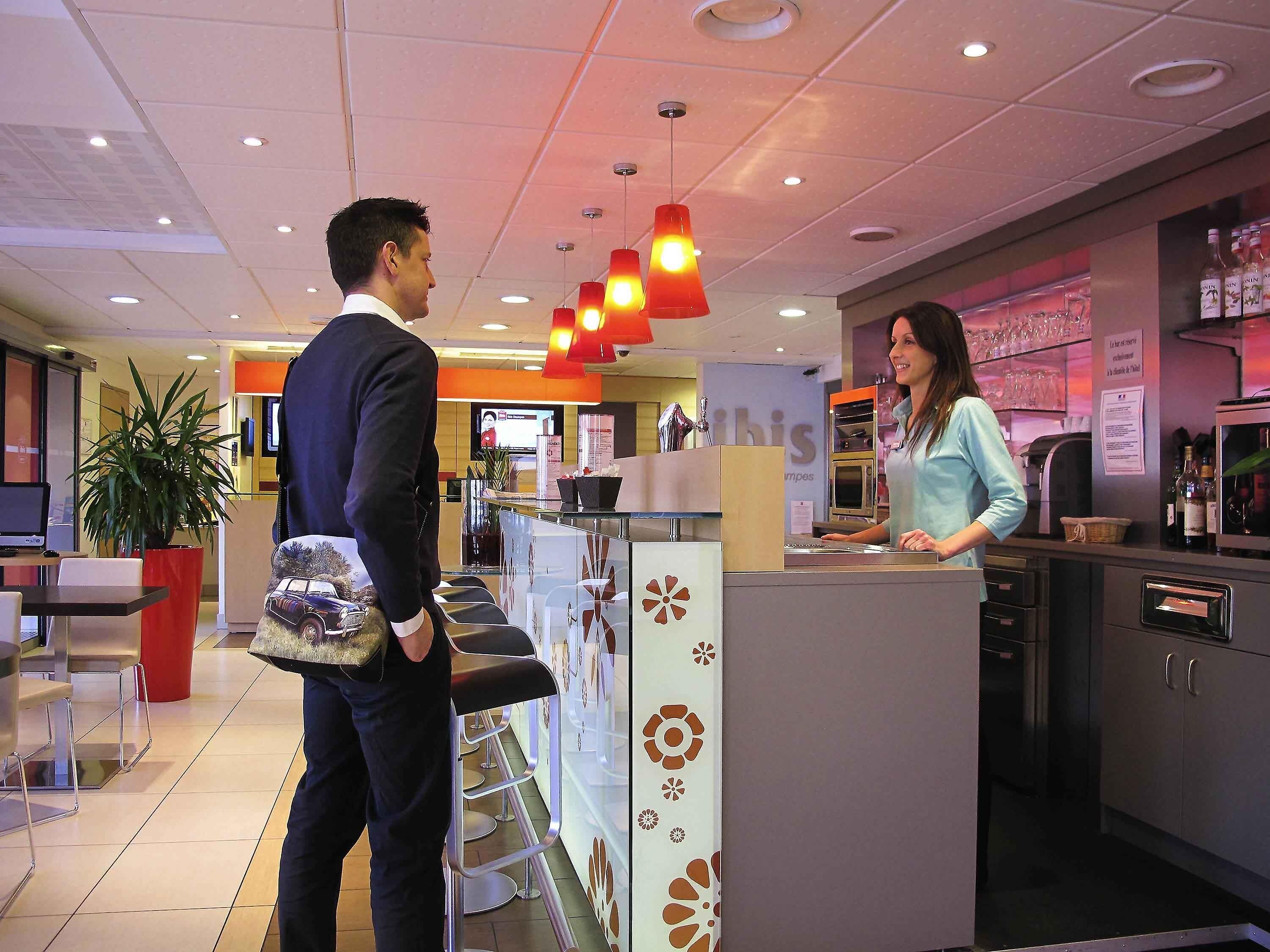 Un moderno vestíbulo de hotel con recepción, zona de estar y bar.