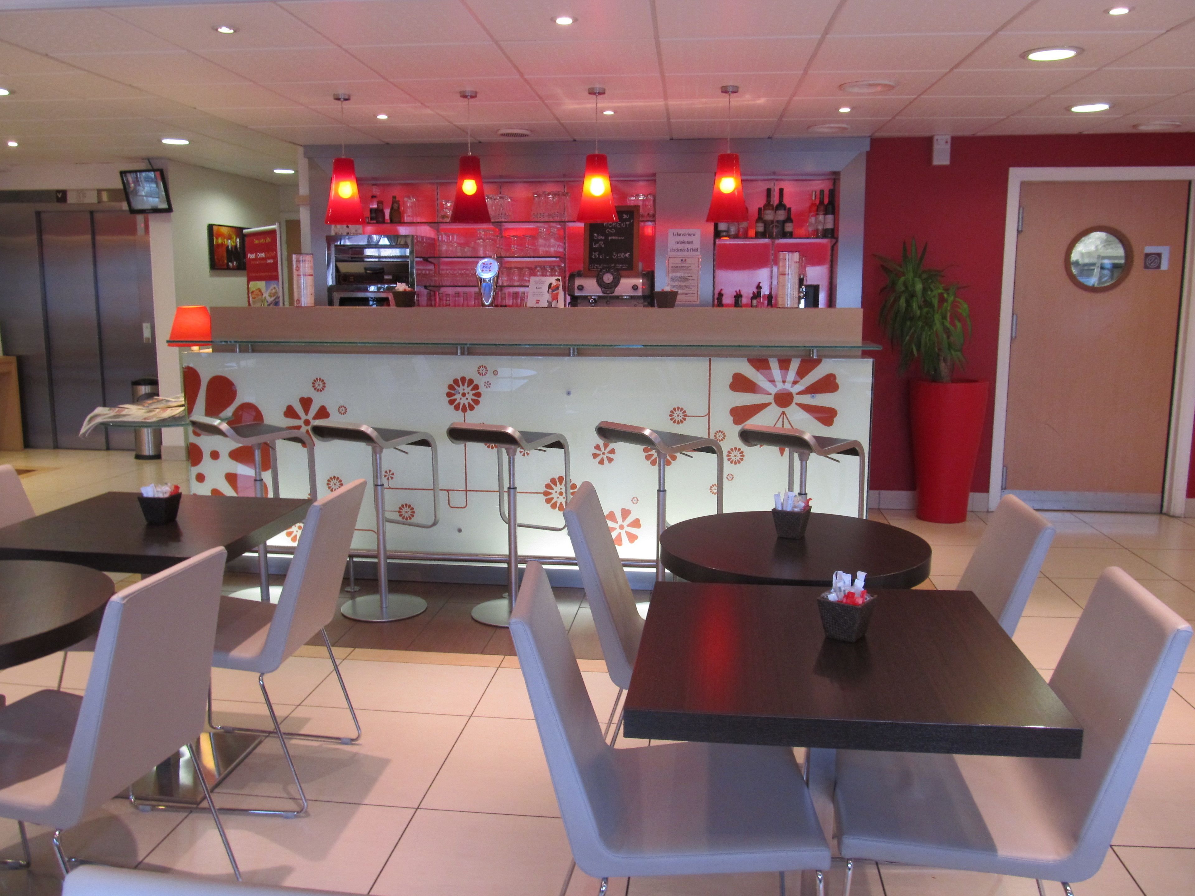 Un restaurante con zona de bar, varias mesas y sillas, y una decoración temática roja y blanca.