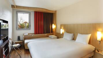 Habitación de hotel con dos camas, un escritorio, un televisor y una ventana con cortinas.