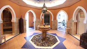 A lobby with a central fountain, arched doorways, and a tiled floor. - Hotels & Appartments Feuerschiff (3114375) (Langeoog)
