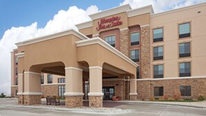 A Hampton Inn & Suites building with a beige exterior, stone accents, and a covered entrance area.