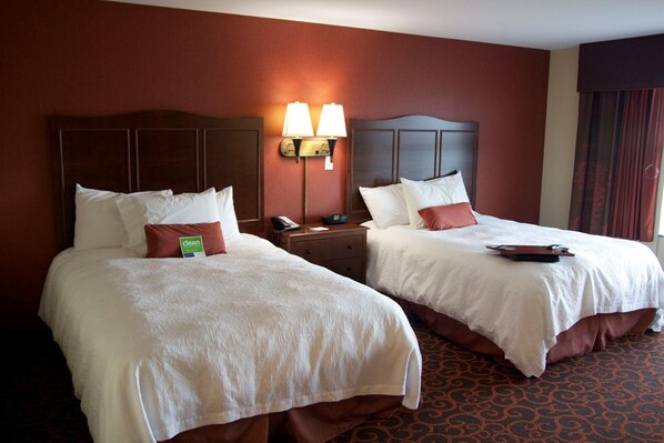 Two double beds with white linens, a nightstand with a lamp, and a "clean" sign.