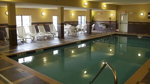 A hotel pool area with lounge chairs, a pool, and a reception desk.