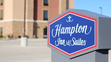 A Hampton Inn & Suites sign with a clear view of the building in the background.