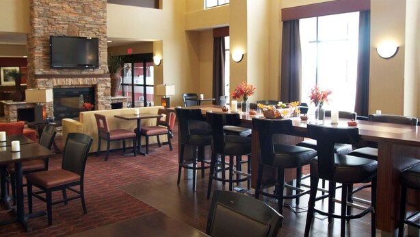A spacious lobby with a stone fireplace, a flat-screen TV, and a bar area with stools and a high table.
