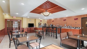 A restaurant with multiple tables and chairs, a kitchen area, and an exit sign. - Best Western Plus Flowood Inn & Suites (Flowood)