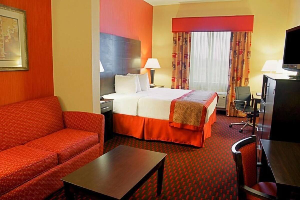 Ein Hotelzimmer mit Bett, einer Sitzecke, Schreibtisch, Stuhl und Fernseher.