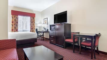 A hotel room with a bed, a desk, a TV, and a dining area.