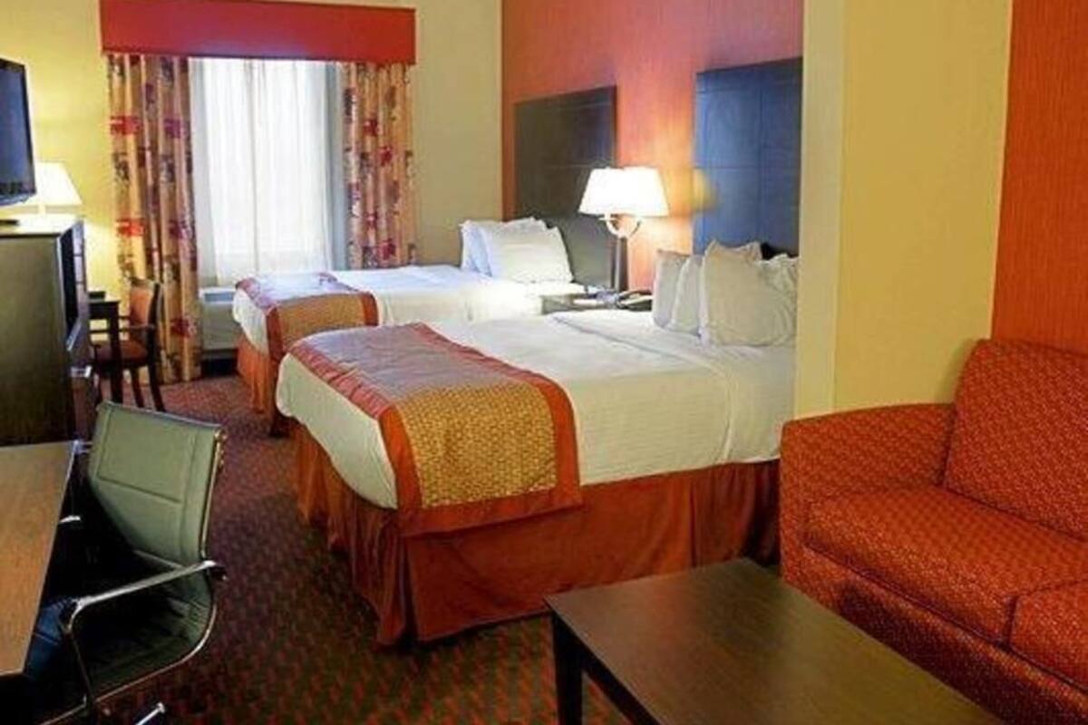 Ein Hotelzimmer mit zwei Betten, einem Schreibtisch, einem Sessel und einem Schlafsofa.