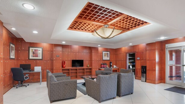 A lobby with a seating area, a desk with a computer, a television, and a vending machine. - Best Western Plus Flowood Inn & Suites (Flowood)