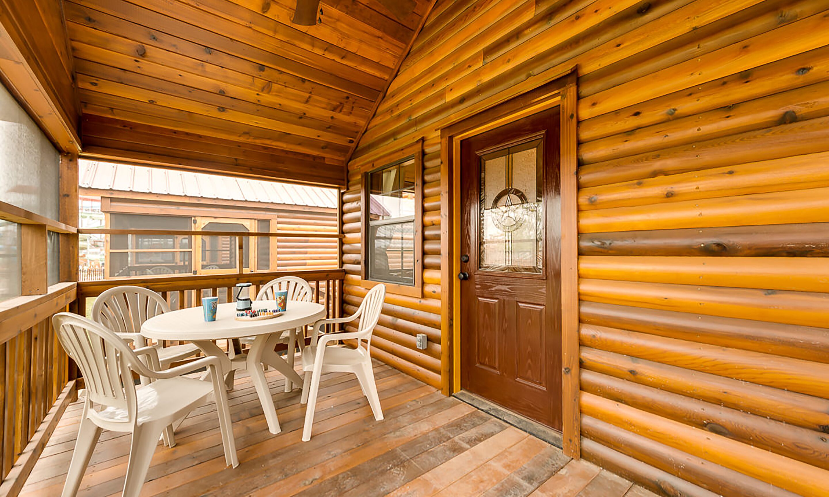 A wooden cabin with a round table and four chairs on a porch.