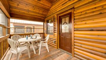 A wooden cabin with a round table and four chairs on a porch.