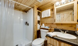 A wooden cabin bathroom with a bathtub, toilet, and sink.