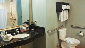 A bathroom with a sink, mirror, toilet, and shower.