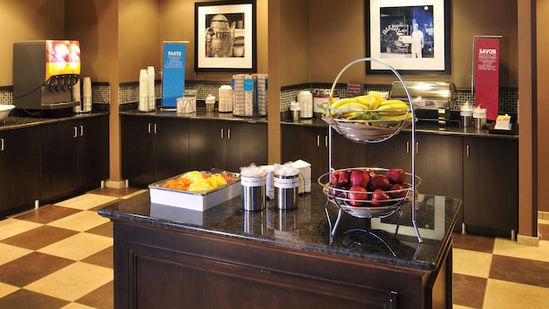 Une cuisine d’hôtel équipée d’une machine à café, de corbeilles de fruits et d’un espace dédié au café.