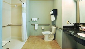 Bathroom features a shower, toilet, and sink with a glass door and towel racks.