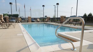 Une piscine dotée de chaises longues et d’une rambarde de sécurité en métal.