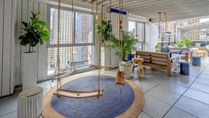 A spacious room with a large window, a hanging swing, and a round rug.