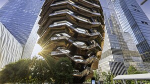 A modern, multi-faceted building with a unique, angular design, surrounded by other high-rise structures.