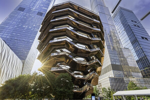 Um edifício moderno e multifacetado com um design angular distinto, rodeado por outros edifícios altos.