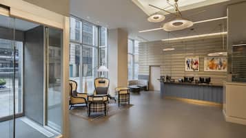 A modern hotel lobby with large windows, a reception desk, and seating areas.