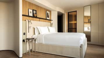 A modern bedroom with a large bed, a bedside table, a wooden panel wall, and a wardrobe.