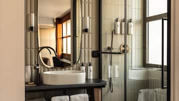 Une salle de bain moderne avec un grand miroir, un lavabo et une douche séparée par une paroi de verre.