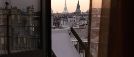 Vista desde una ventana con vistas a un paisaje urbano, donde se distingue la Torre Eiffel al fondo.