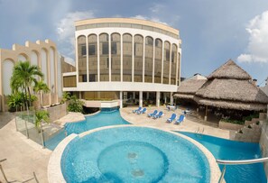 A resort with a large swimming pool, lounge chairs, and a building with arched windows. - DoubleTree by Hilton Iquitos (Iquitos)