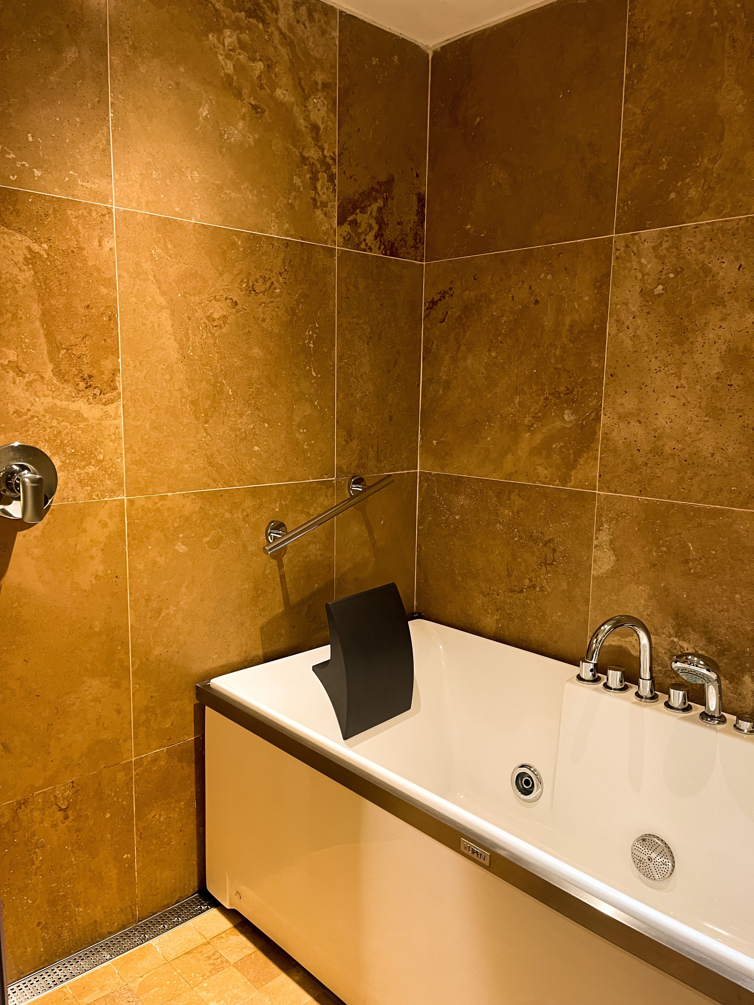Un baño con una bañera blanca, una toalla negra y un grifo cromado.