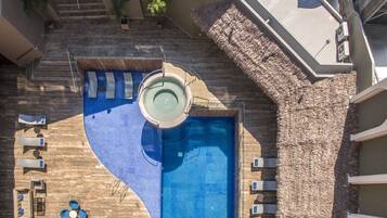 A swimming pool with a unique design, surrounded by lounge chairs and umbrellas.