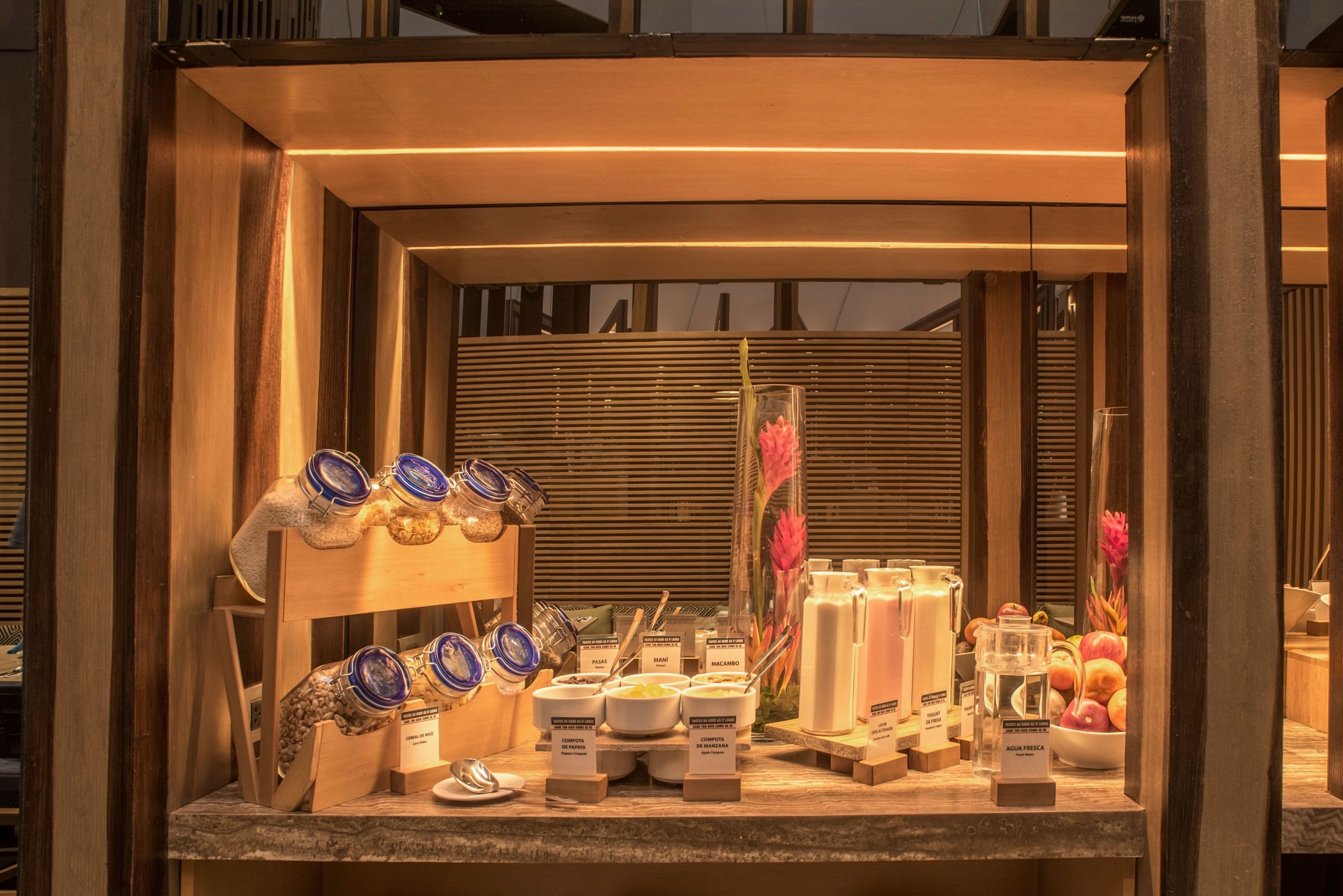 Een ontbijtbuffet met potten met sauzen, kommen met ontbijtgranen en vers fruit.
