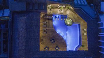 Vista aérea de un hotel con una piscina grande y de forma peculiar, zonas de estar al aire libre y una escalera que conduce a las plantas superiores.