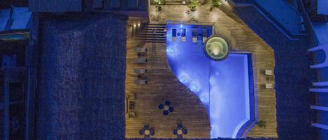 Vista aérea de un hotel con una piscina grande y de forma peculiar, zonas de estar al aire libre y una escalera que conduce a las plantas superiores.