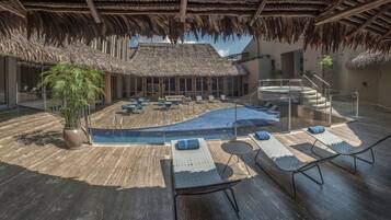 Zona de piscina con sillones de descanso, bañera de hidromasaje y una escalera que lleva a un nivel superior.