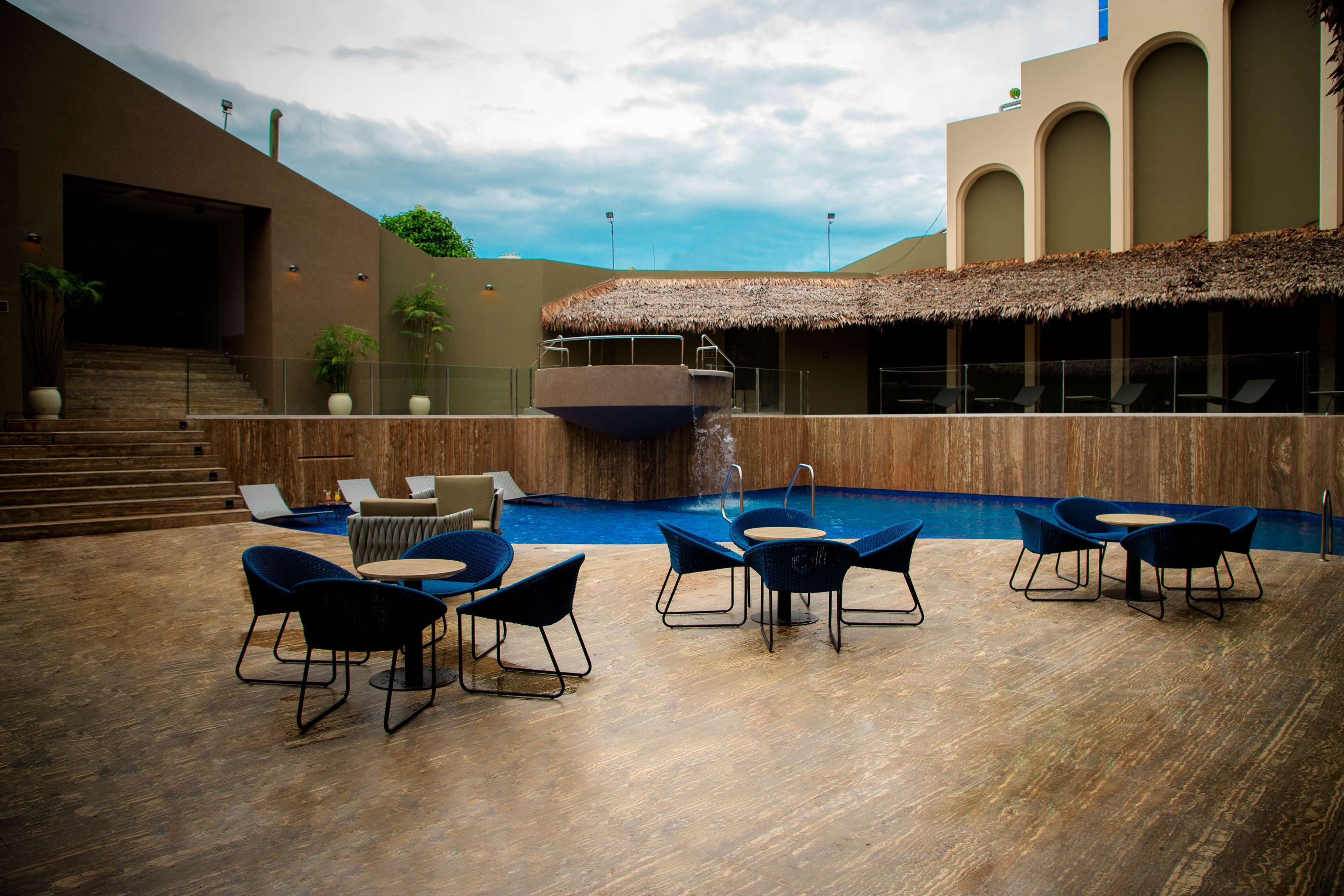 An outdoor pool area with lounge chairs and a thatched-roof structure.
